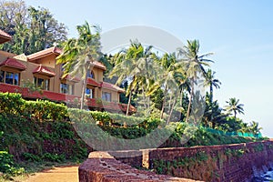 The hotel building with palm trees on an ocean coast in India.