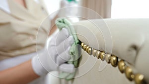 Hotel cleaning. Soft furniture surface and buttons being cleaned by female hands with wipe. Close-up view of woman