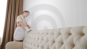 Hotel cleaning. Soft furniture surface is cleaned by pretty maid with wipe in hands. woman removing dirty stain from