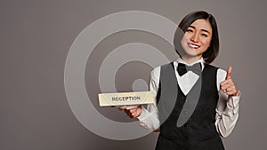 Hotel concierge holding sign to indicate direction for reception desk