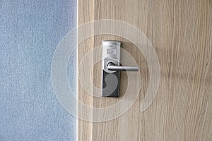 Hotel electronic lock on wooden door and with a blue wall.