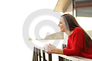 Hotel guest contemplating beach holding a coffee cup