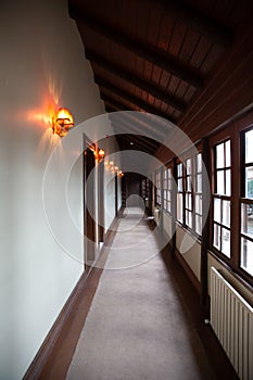 A hotel hallway with brown wooden windows and ceiling decorated with appliques and a grey carpet