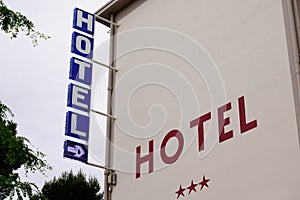 Hotel light arrow sign blue and red text and three stars on Building in tourist city