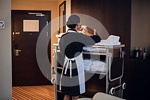 Hotel maid working with cleaning cart and cleaning supplies