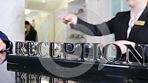 Hotel manager giving key to hotel room at reception, close-up. Blurred footage. Male guest receiving hotel room key at