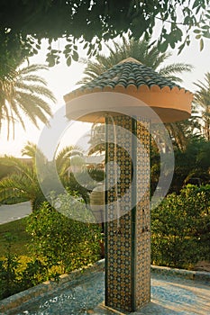 Hotel poolside shower made from beautiful oriental-style tiles amid tropical greenery