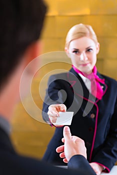 Hotel receptionist check in man giving key card