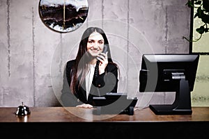 Hotel receptionist. Modern hotel reception desk with bell. Happy female receptionist worker standing at hotel counter and talking