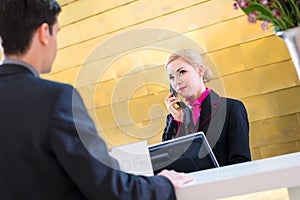 Hotel receptionist with phone and guest