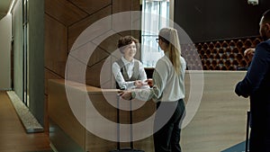 Hotel receptionist welcoming guests talking to businesspeople giving key cards