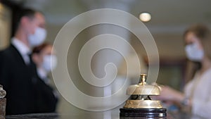 Hotel receptionists wearing medical masks, checking in young woman at the hotel room