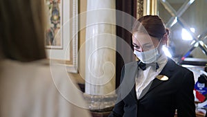 Hotel receptionists wearing medical masks, checking in young woman at the hotel room