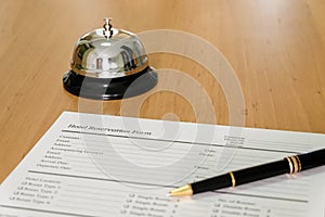 Hotel reservation form and luxury pen at reception concierge desk. With a bell ring for guest to call for a service, attention.
