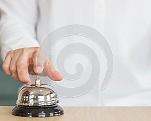 Hotel restaurant bell service on concierge customer reception counter with business person ringing pressing bell button calling