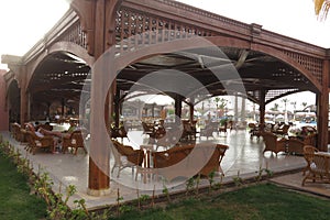 The hotel restaurant is made of wooden beams and planks. Covered outdoor terrace with seating and decorative wooden fencing.