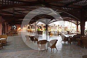 The hotel restaurant is made of wooden beams and planks. Covered outdoor terrace with seating and decorative wooden fencing.