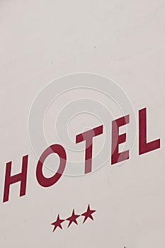 Hotel sign text red and three stars in wall city building facade in french tourist town