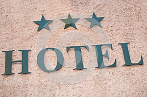 Hotel signage with three stars on stoned wall