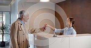 Hotel staff welcome visitor and giving room key after check in