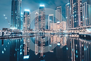 Hotels and apartment residential buildings panoramic view in Dubai Marina Creek Harbour at night with reflections in