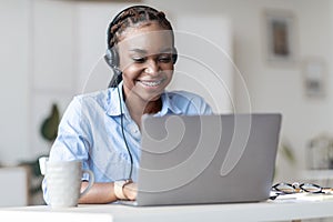 Hotline Operator. African woman call center worker in headset consulting client online