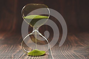 Hourglass as time passing concept for business deadline, urgency and running out of time, on wooden background
