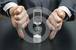 Hourglass on the background of a business man. distribution of time for work. time to make decisions