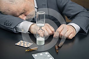 Hourglass on the background of a tired and depressed business man. distribution of time for work. time to make decisions. late