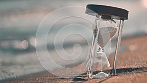 Hourglass at beach coast as time passing concept for business deadline, urgency and running out of time