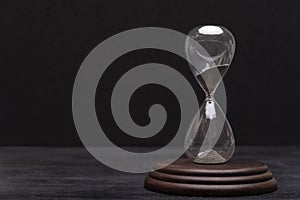 Hourglass on black background. Urgency and outcome of time. Time management
