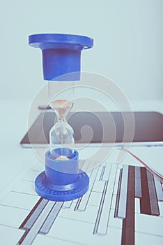 Hourglass. Businessman working in the office in the background. Concept time is money.