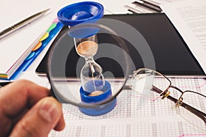 Hourglass. Businessman working in the office in the background. Concept time is money.