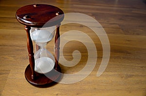 Hourglass, clock in front of wooden background with a copy space.