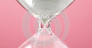 Hourglass closeup on a pink background, concept on the theme of the passage of time