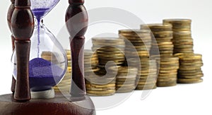 Hourglass and coins isolated on white background