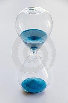 Hourglass containing blue sand isolated on white background