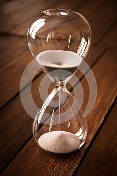 Hourglass containing white sand on a rustic wooden board