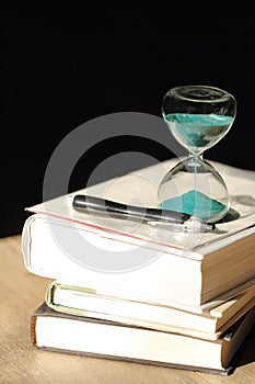 Hourglass countdown with books and a pen
