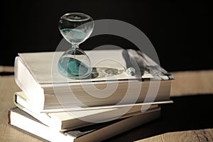 Hourglass countdown with books and a pen