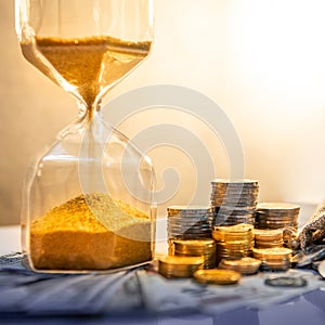Hourglass and currency on table, Time Investment
