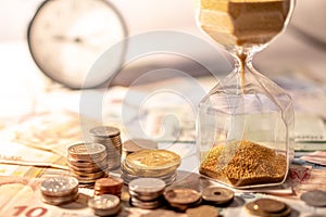 Hourglass and currency on table, Time Investment concept