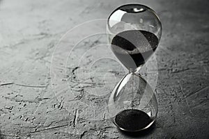 Hourglass on dark background, closeup. Urgency and running out of time concept