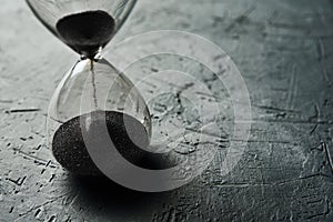 Hourglass on dark background, closeup. Urgency and running out of time concept