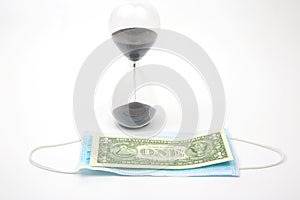 Hourglass, dollar and medical mask on a white background. time and protection from the virus. financial losses due to the virus