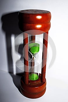 Hourglass with green sand on white background