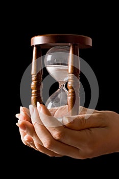 Hourglass in hands on a black