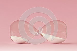 Hourglass lying on pink background - Concept of time and woman