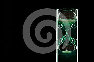 Hourglass of modern design with colored liquid on a dark background