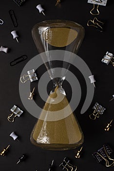 Hourglass with office accessories. Business, work. Black style, concept of running out of time